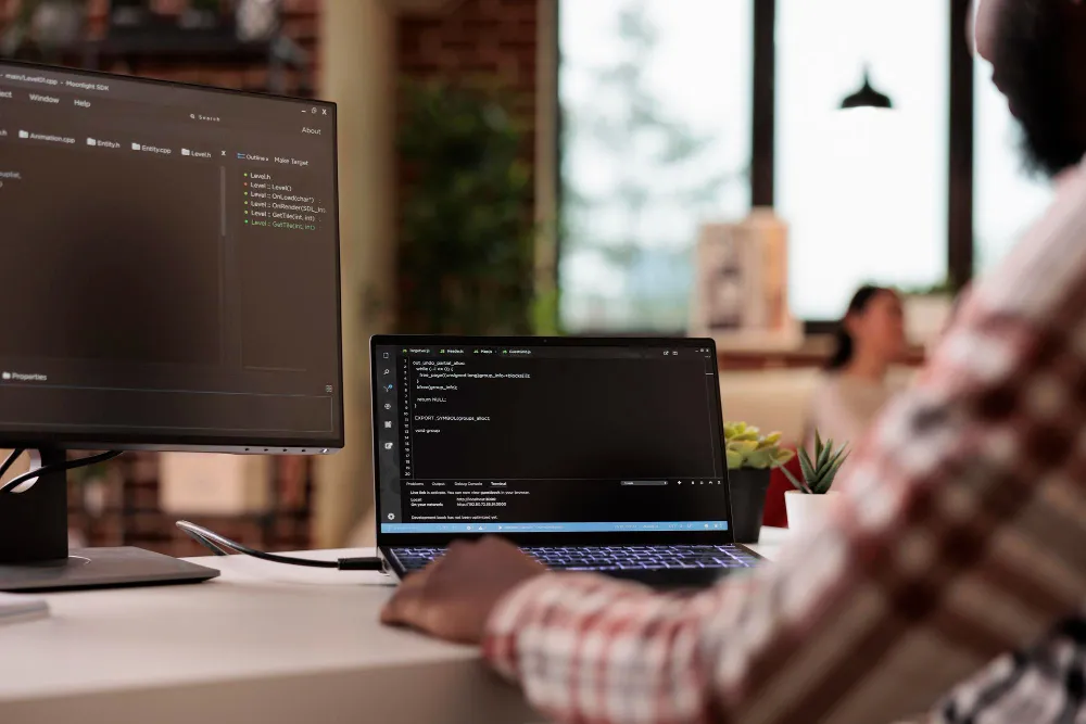 Programmer coding in C++ on a dual monitor development setup