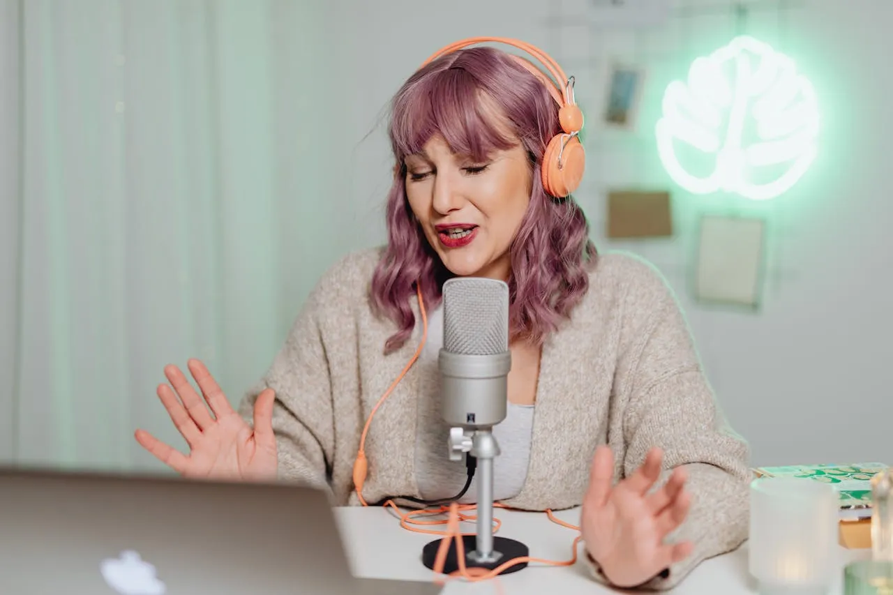Woman with purple hair recording podcast with neon leaf background and microphone.