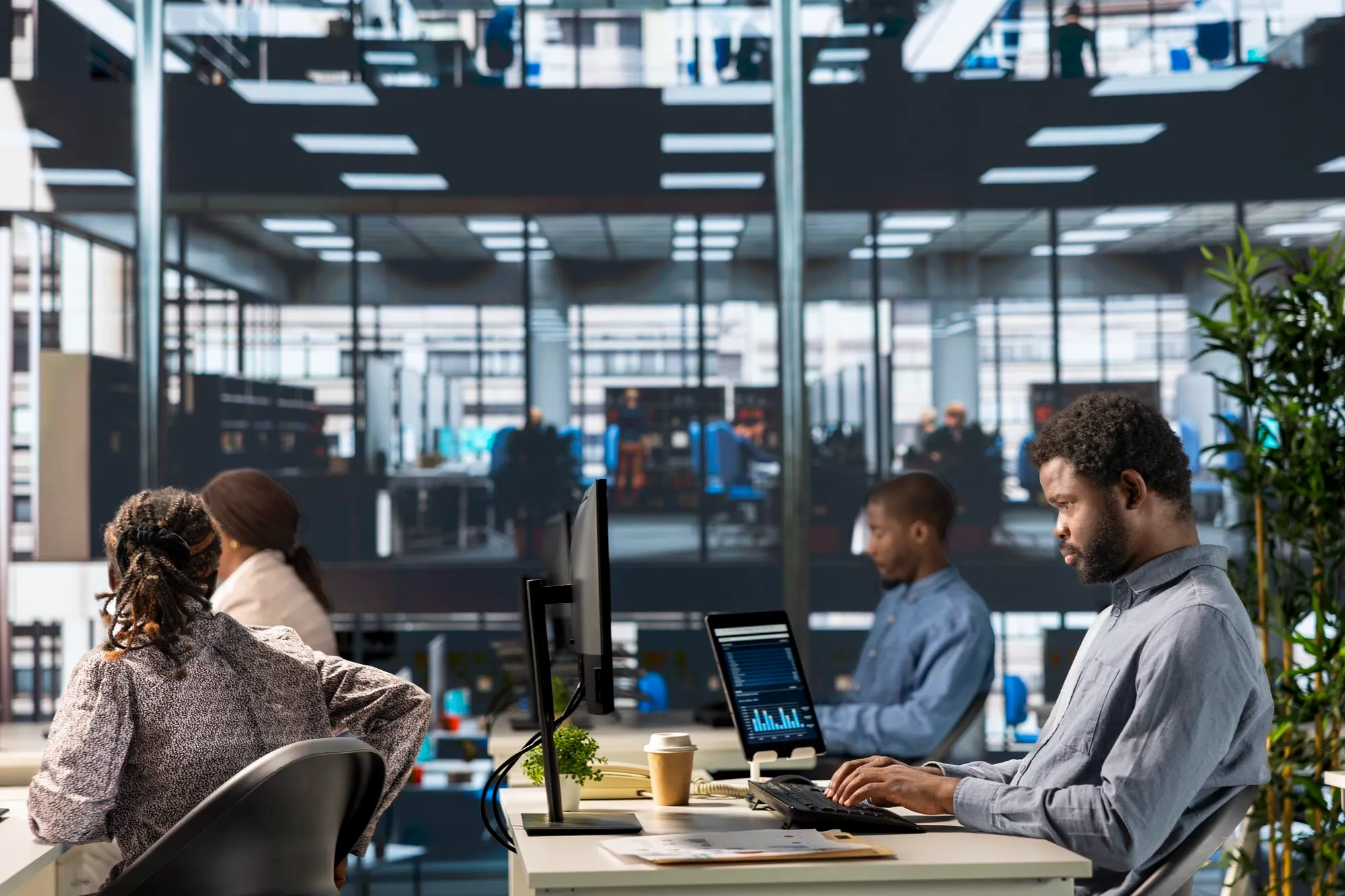 Diverse office team collaborating on laptops, analyzing data in a bright modern workspace.